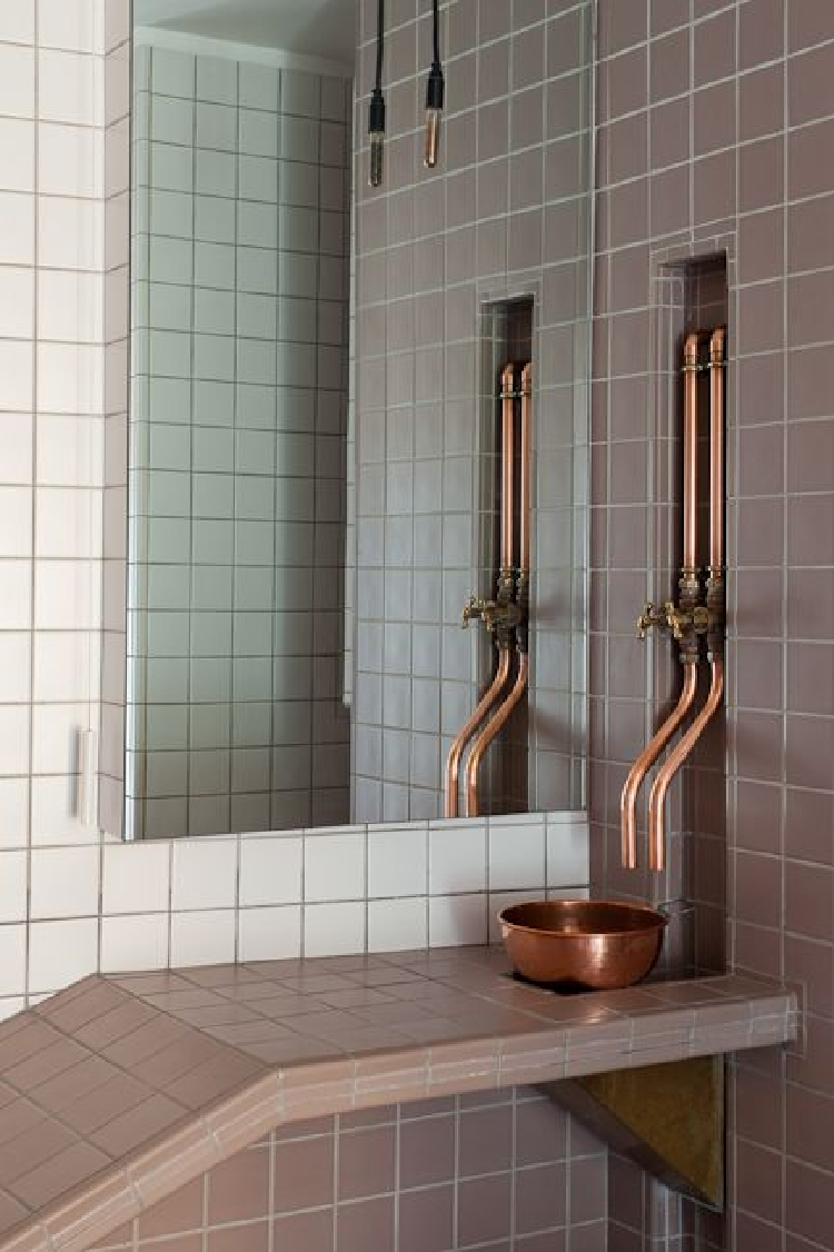 Earthy tiles with exposed copper pipes as a home accent