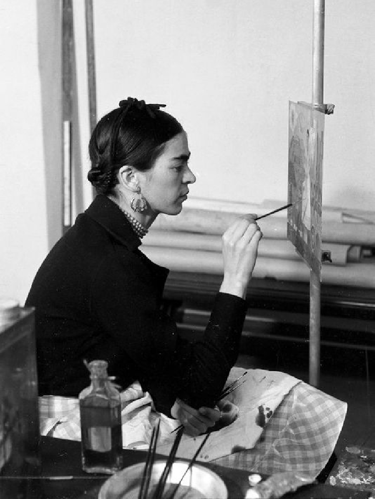 Frida painting in her studio